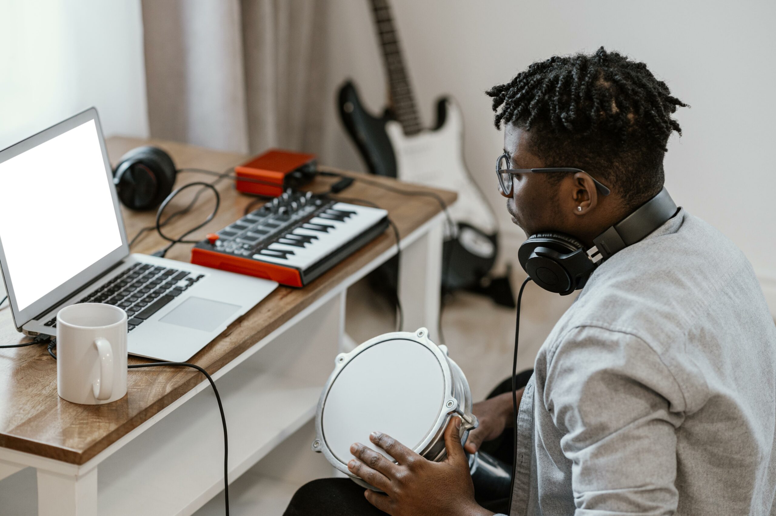 male-musician-home-playing-drums-mixing-with-laptop